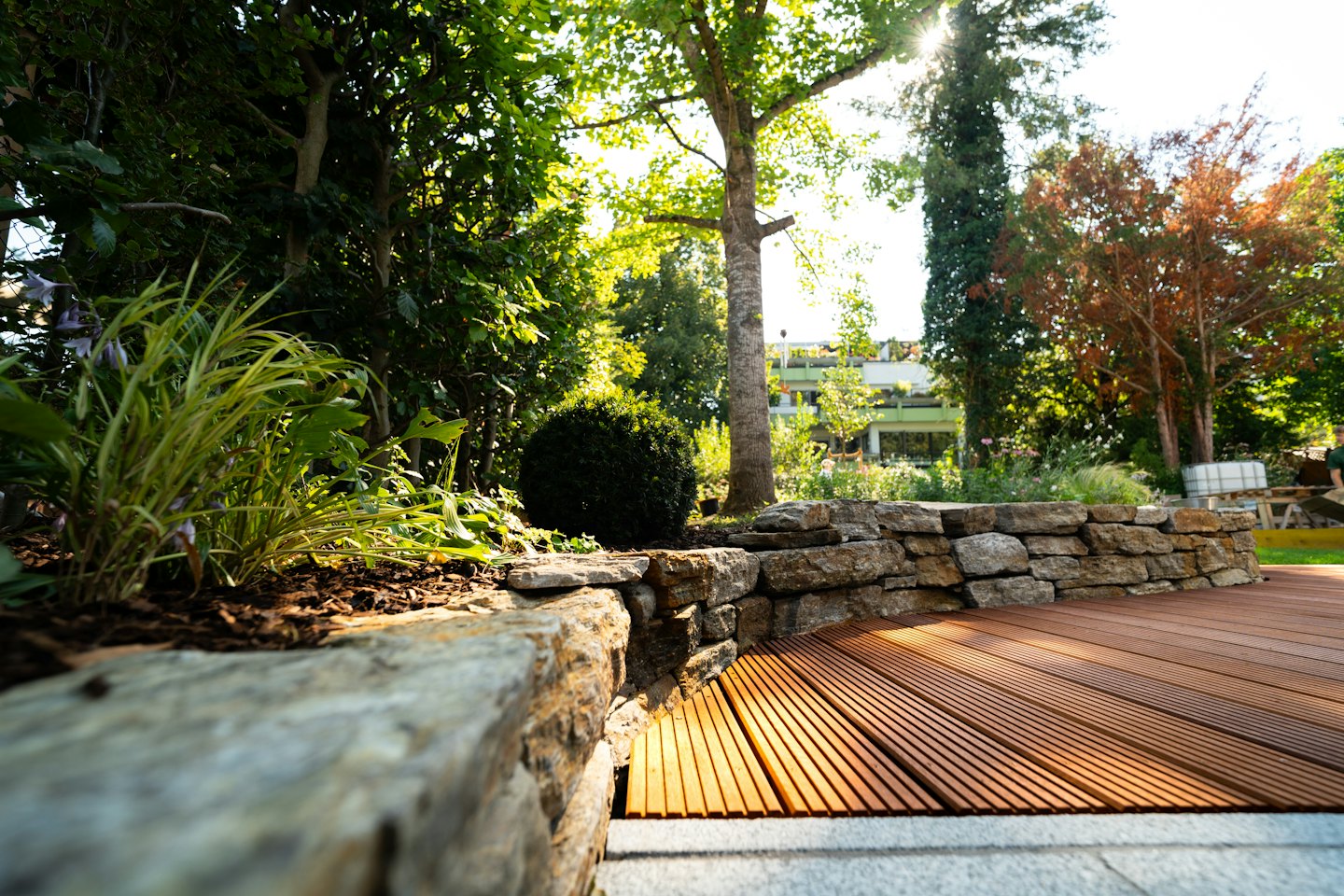 Moderner Garten mit Steinmauern und Holzdeck.